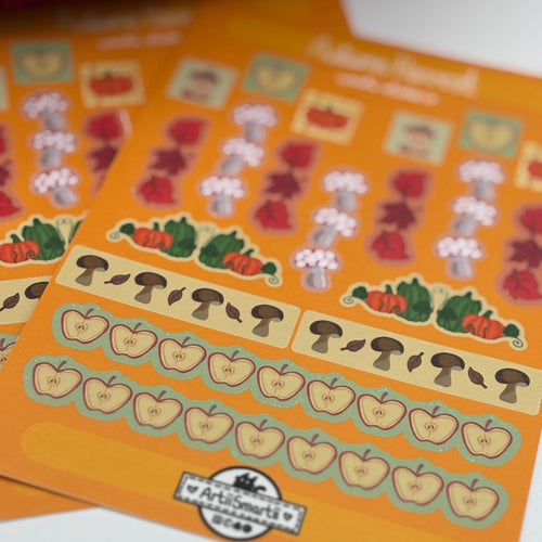 A close-up of two orange sticker sheets featuring autumn-themed illustrations, including pumpkins, mushrooms, acorns, and flowers, with a white background.