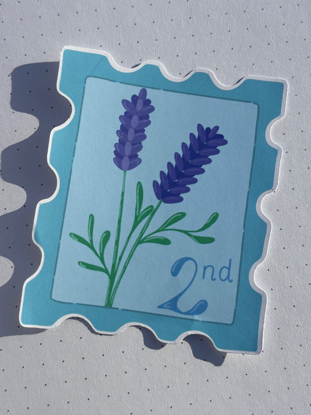 Stamp sticker with lavender design, 2nd class written on it. Blue and purple colouration.