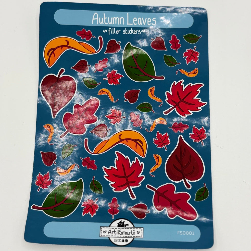 A sheet of 'Autumn Leaves' fuller stickers by Artiismartii, featuring various red, orange, and green leaf designs on a dark blue backing card.