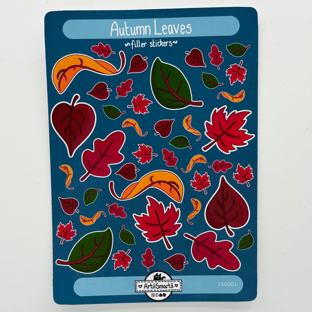 A sheet of 'Autumn Leaves' filler stickers by Art Smarts, featuring various red, green, and orange leaf shapes on a dark blue backing card, photographed flat on a white surface.
