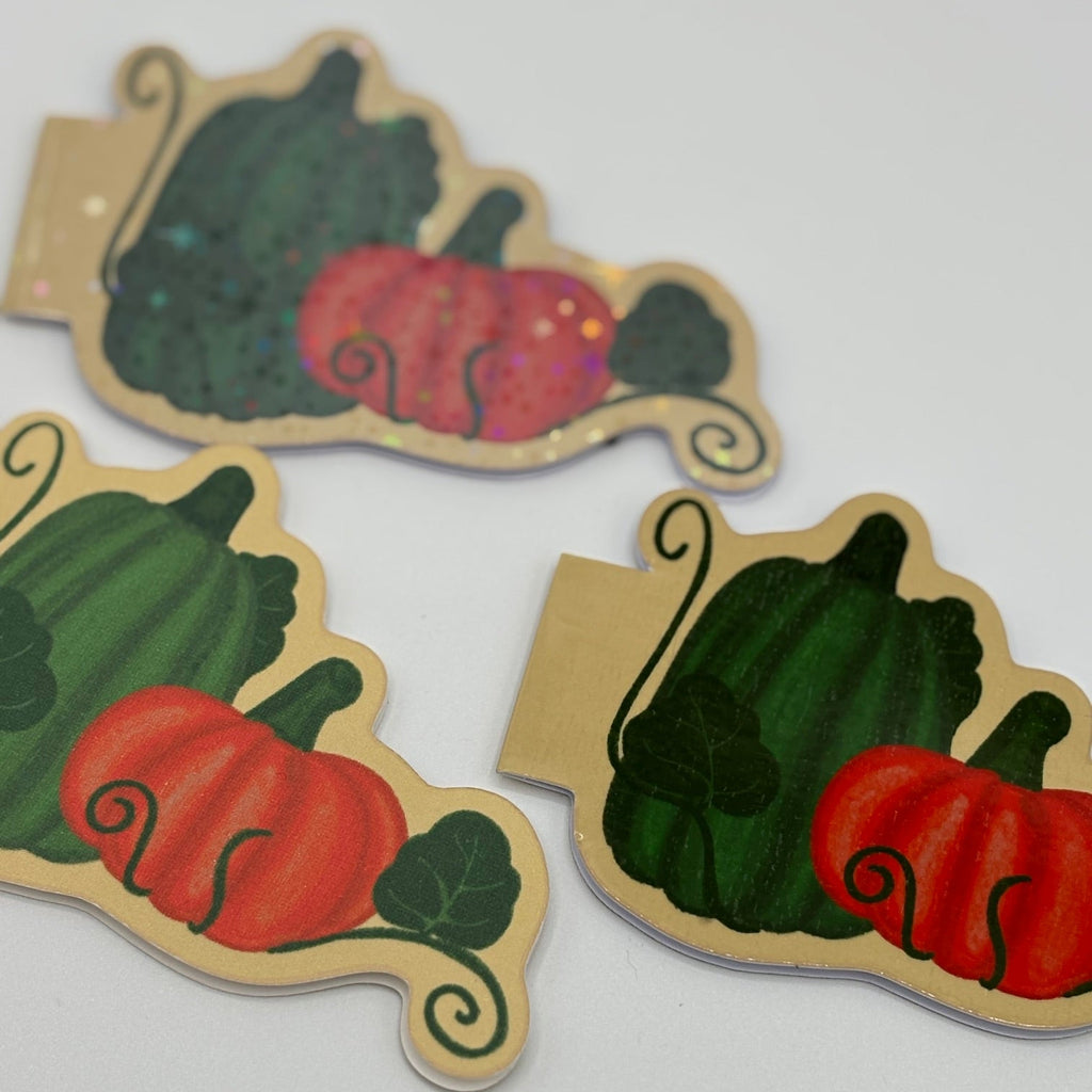 Three autumn-themed paper cutouts shaped like pumpkins and gourds on a plain white background.