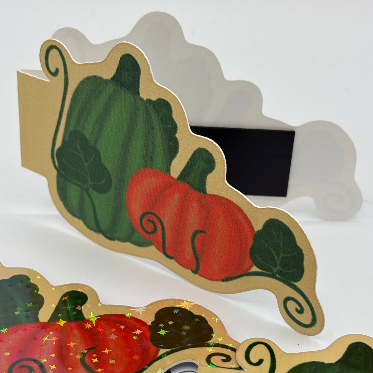 A set of autumn-themed paper cutout signs featuring painted pumpkins and gourds on a beige background, displayed on a white surface.