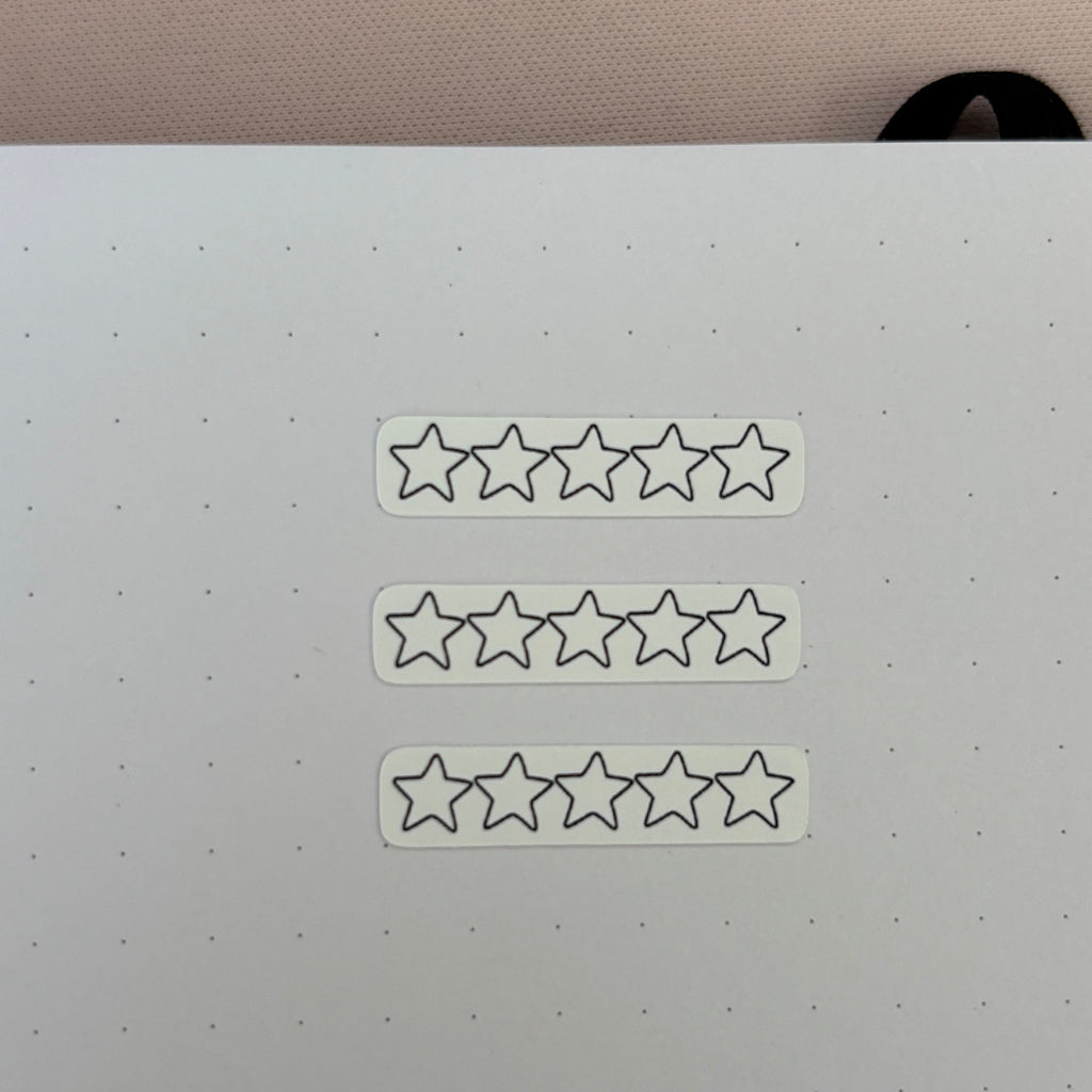 Three white rectangular stickers with five outlined star icons, arranged vertically on a white dotted planner pad.