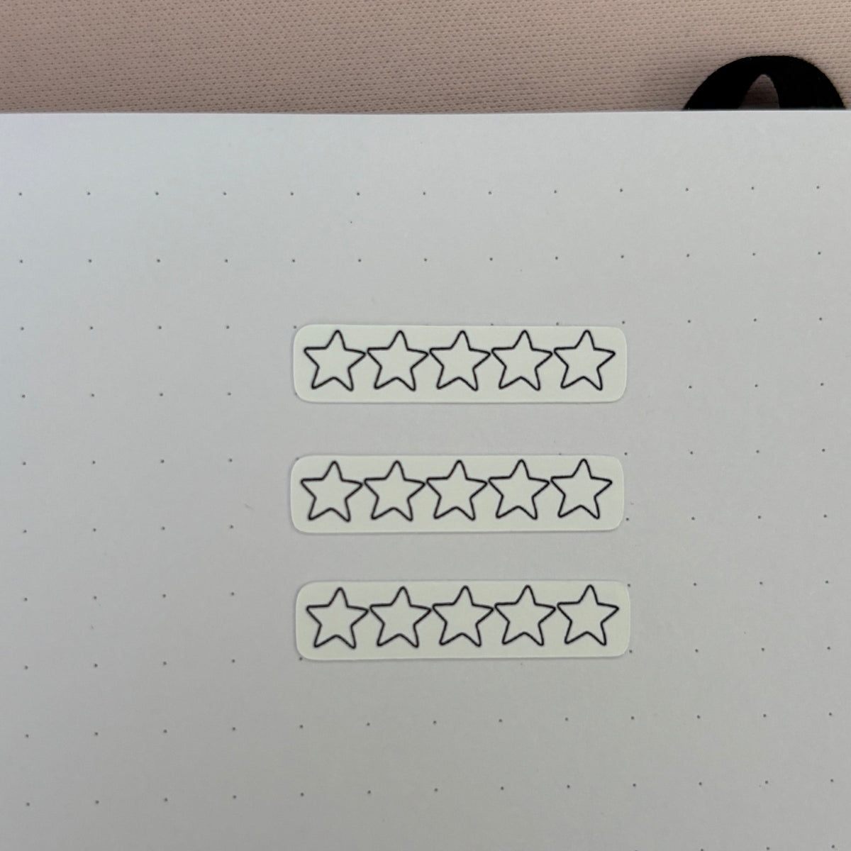 Three white rectangular stickers with five outlined star icons, arranged vertically on a white dotted planner pad.