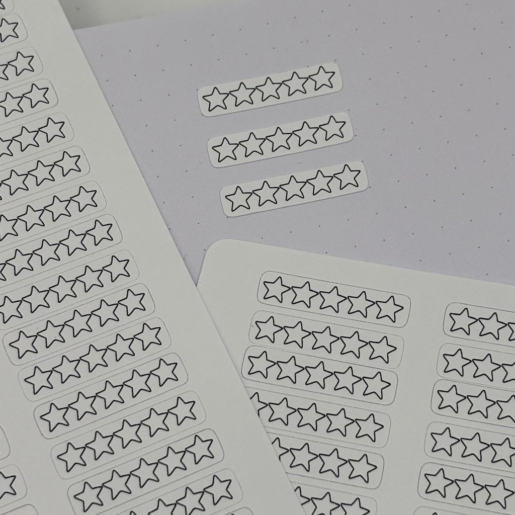 Star-shaped planner stickers on white sheets, arranged on a light gray dotted paper background.