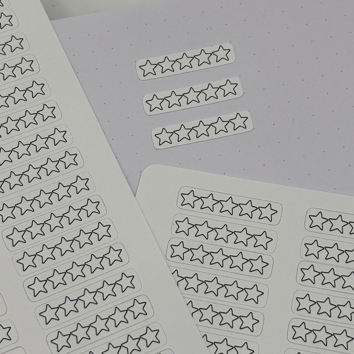 Star-shaped planner stickers on white sheets, arranged on a light gray dotted paper background.