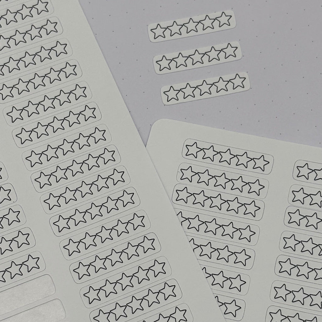 Two sheets of planner stickers featuring rows of outlined one-to-five star rating boxes, with blank rectangular sticker spaces on the left sheet. The sheets are arranged on a light gray background, and the brand name 'planner smarti' is visible on the bottom left.