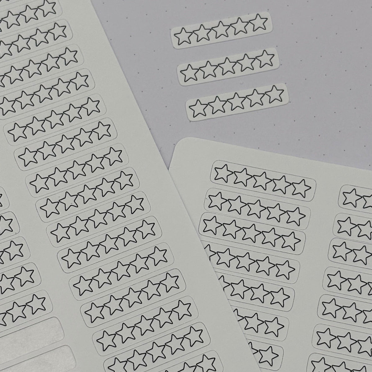 Two sheets of planner stickers featuring rows of outlined one-to-five star rating boxes, with blank rectangular sticker spaces on the left sheet. The sheets are arranged on a light gray background, and the brand name 'planner smarti' is visible on the bottom left.